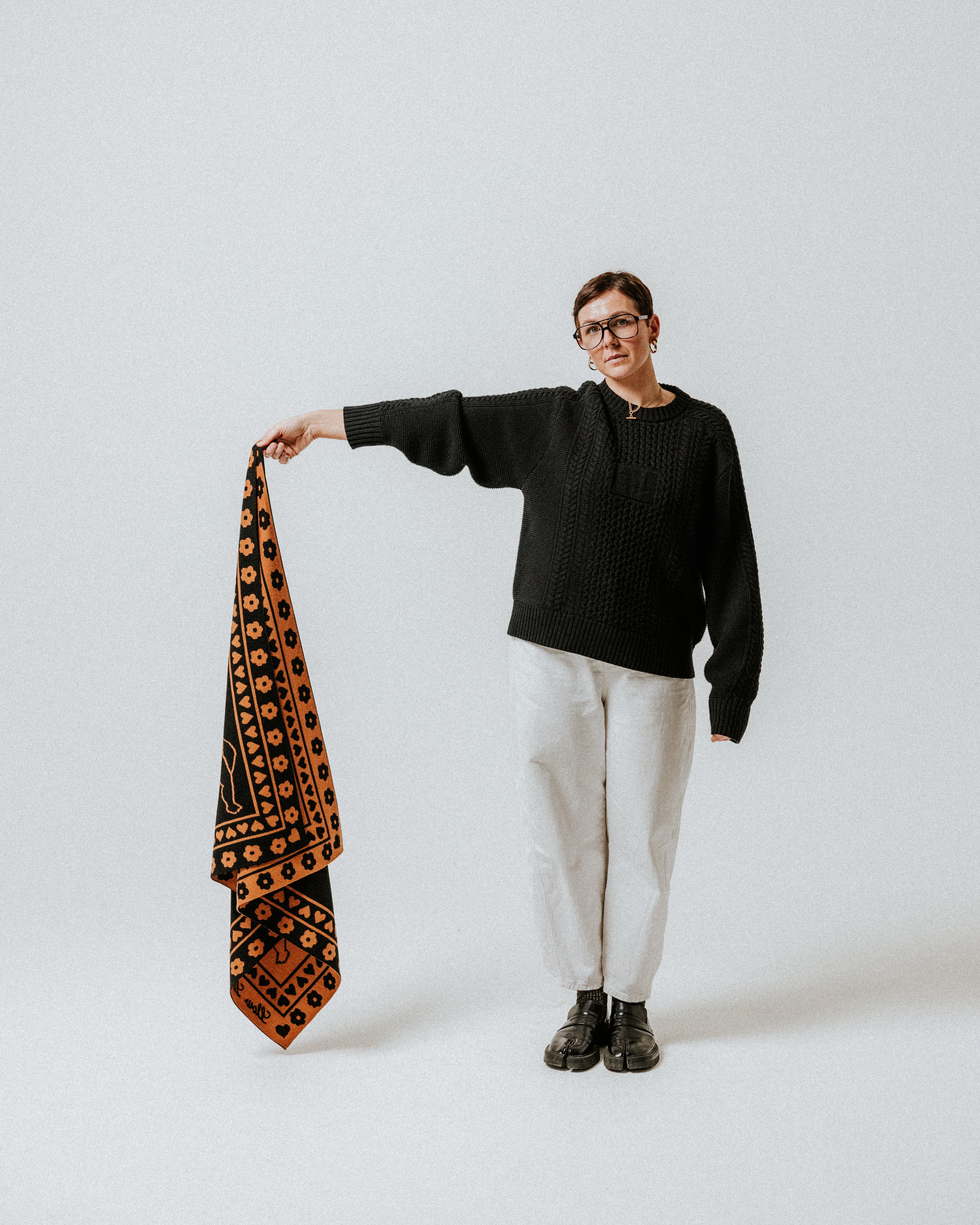 Toffee and black Cherub Bandana Scarf by The Slow Love, featuring an illustrated cherub motif on a soft merino wool knit.