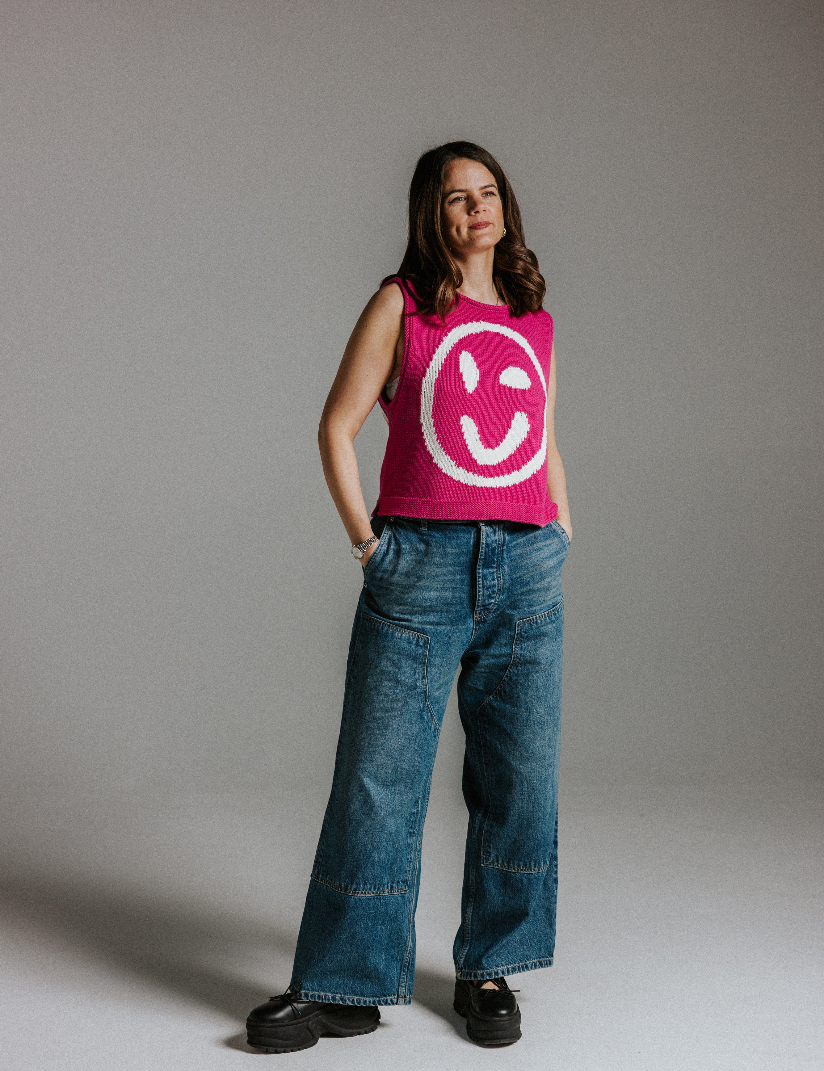 Model wearing pink and white cotton knit tank top with smiley face motif and boxy fit