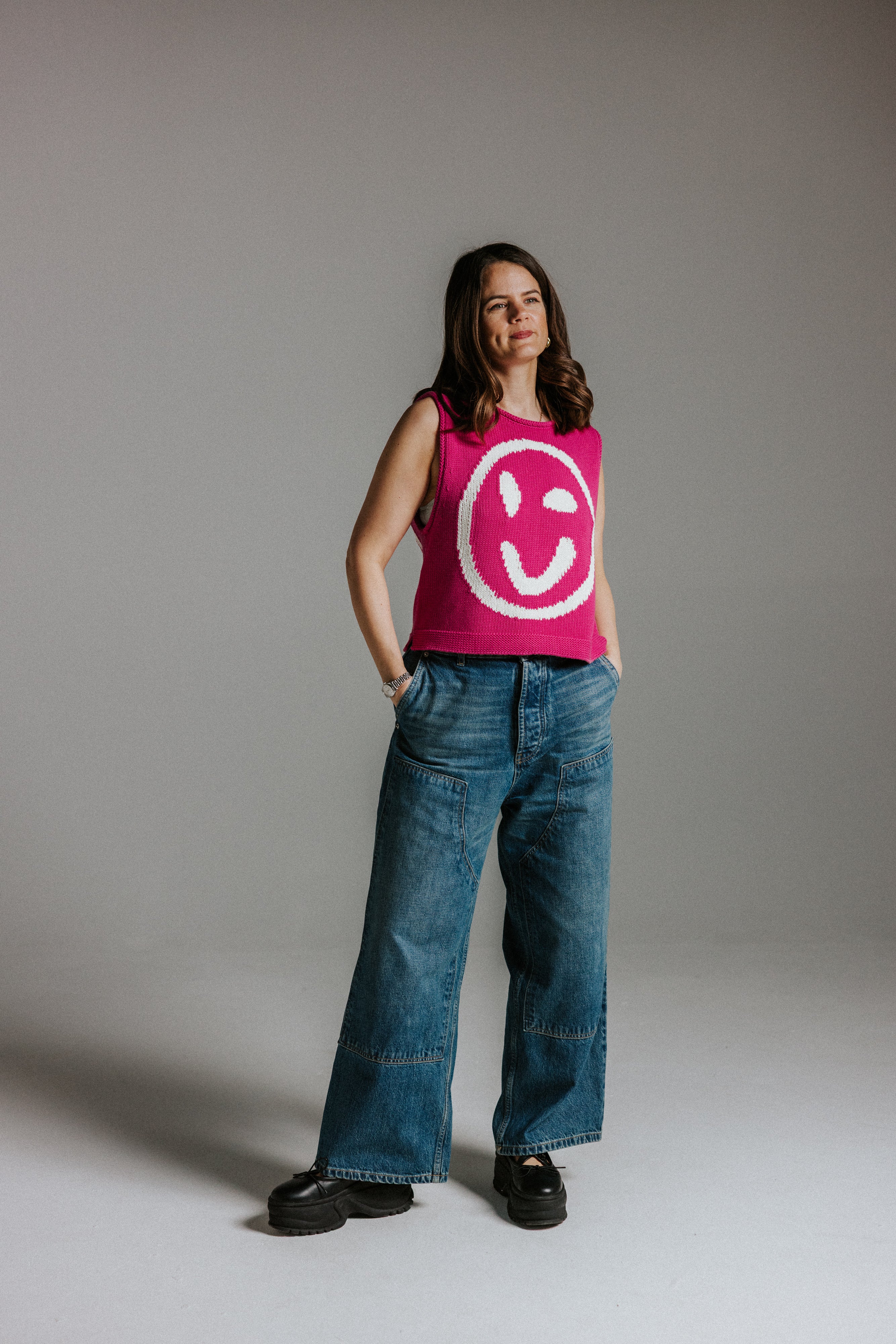 Model wearing pink and white cotton knit tank top with smiley face motif and boxy fit