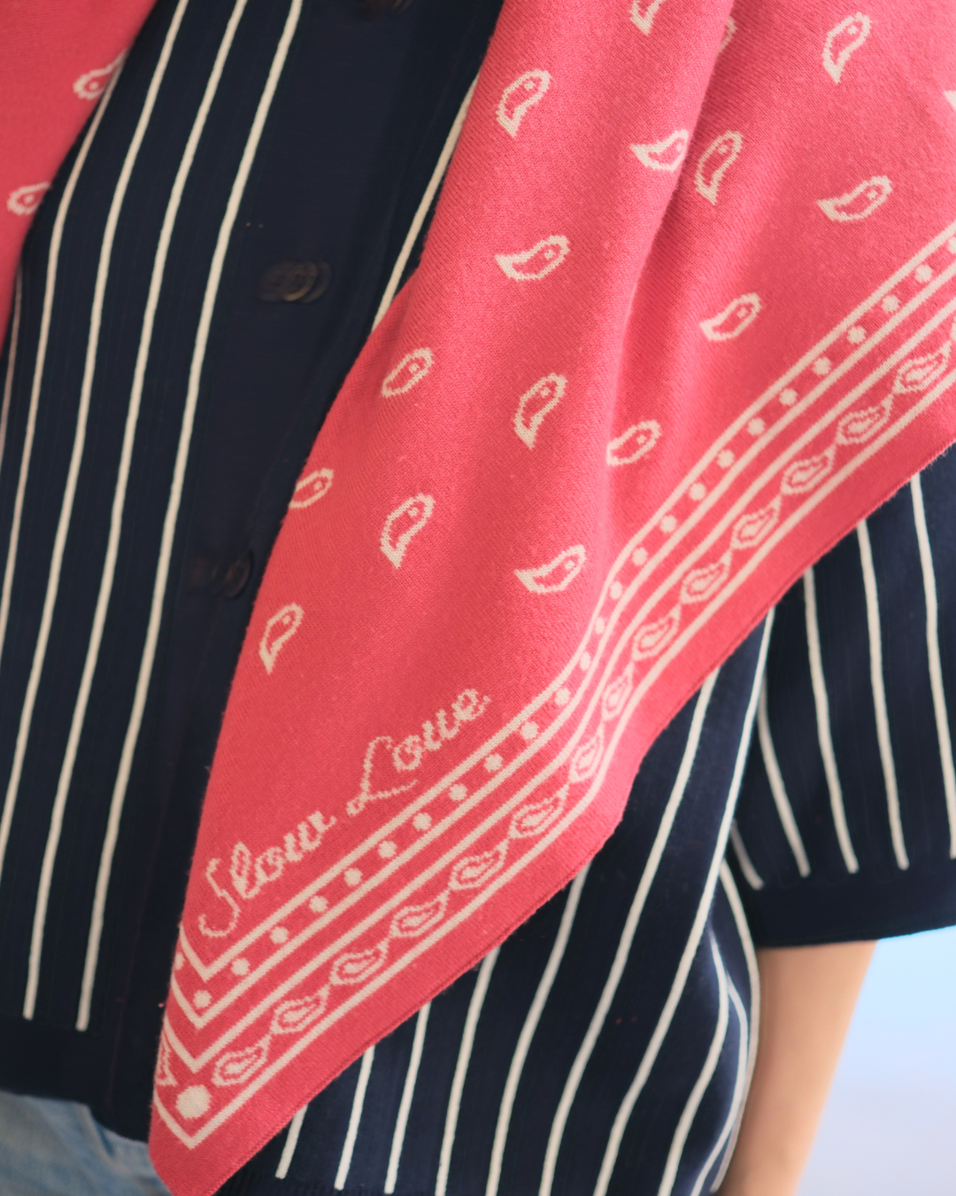 Red merino wool bandana scarf by Slow Love styled around the neck for a warm and colourful finishing touch.