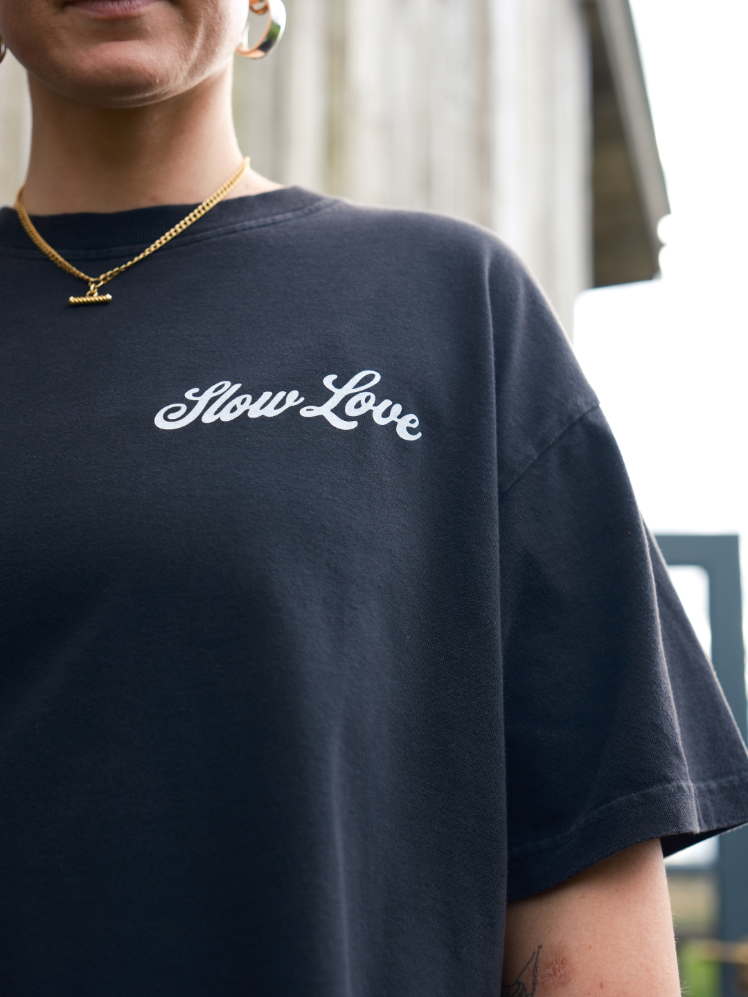 Close-up detail of the SL Script logo on a faded black heavyweight organic cotton t-shirt.