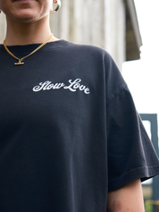Close-up detail of the SL Script logo on a faded black heavyweight organic cotton t-shirt.