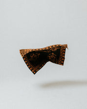 The Slow Love Cherub Bandana Scarf in toffee and black, a soft 100% merino wool accessory for adding warmth and character to winter outfits.