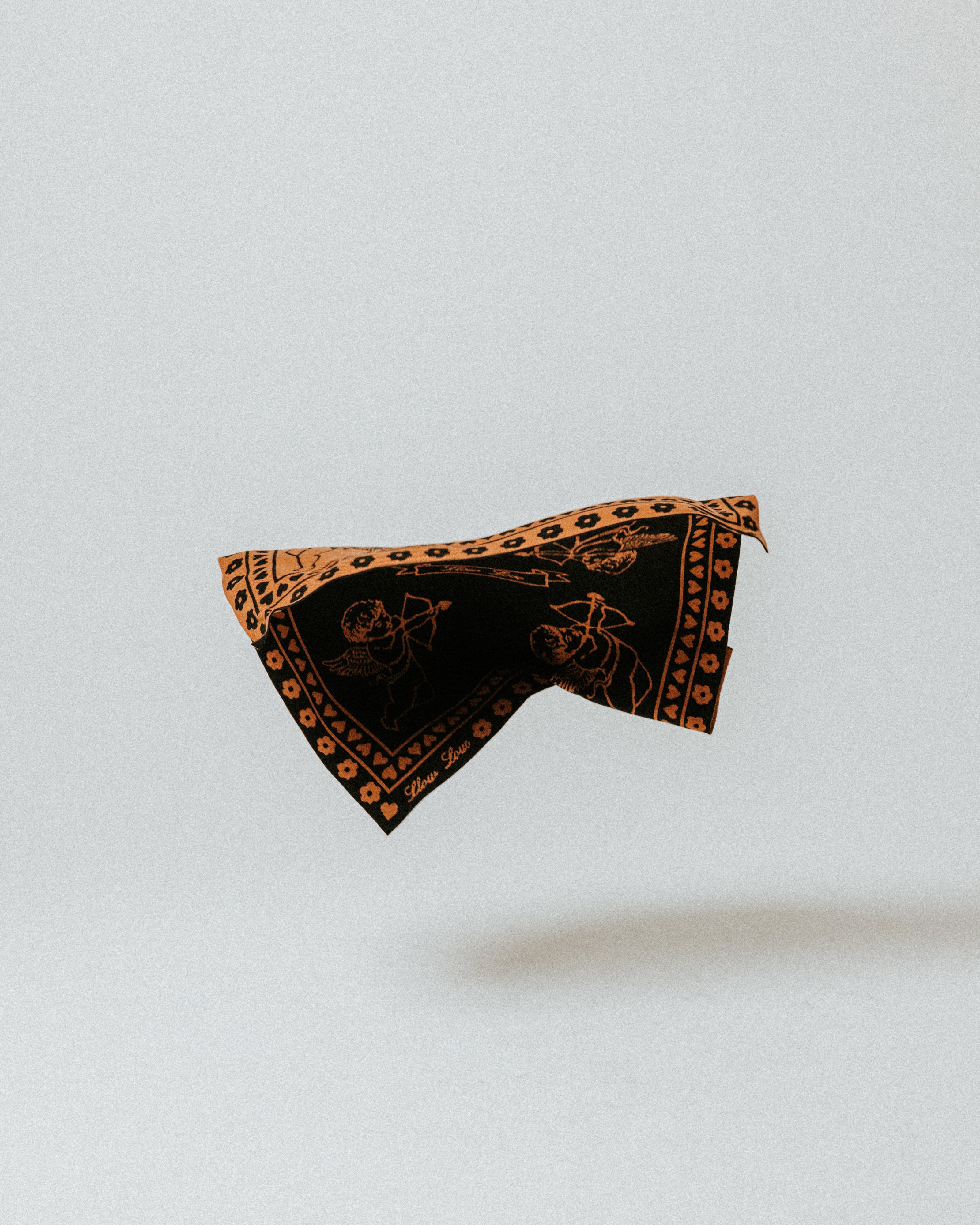 The Slow Love Cherub Bandana Scarf in toffee and black, a soft 100% merino wool accessory for adding warmth and character to winter outfits.