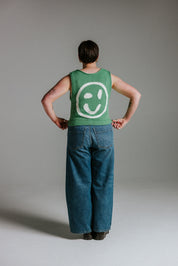 Model wearing green and white boxy cotton knit tank top with smiley motif by Slow Love Knitwear