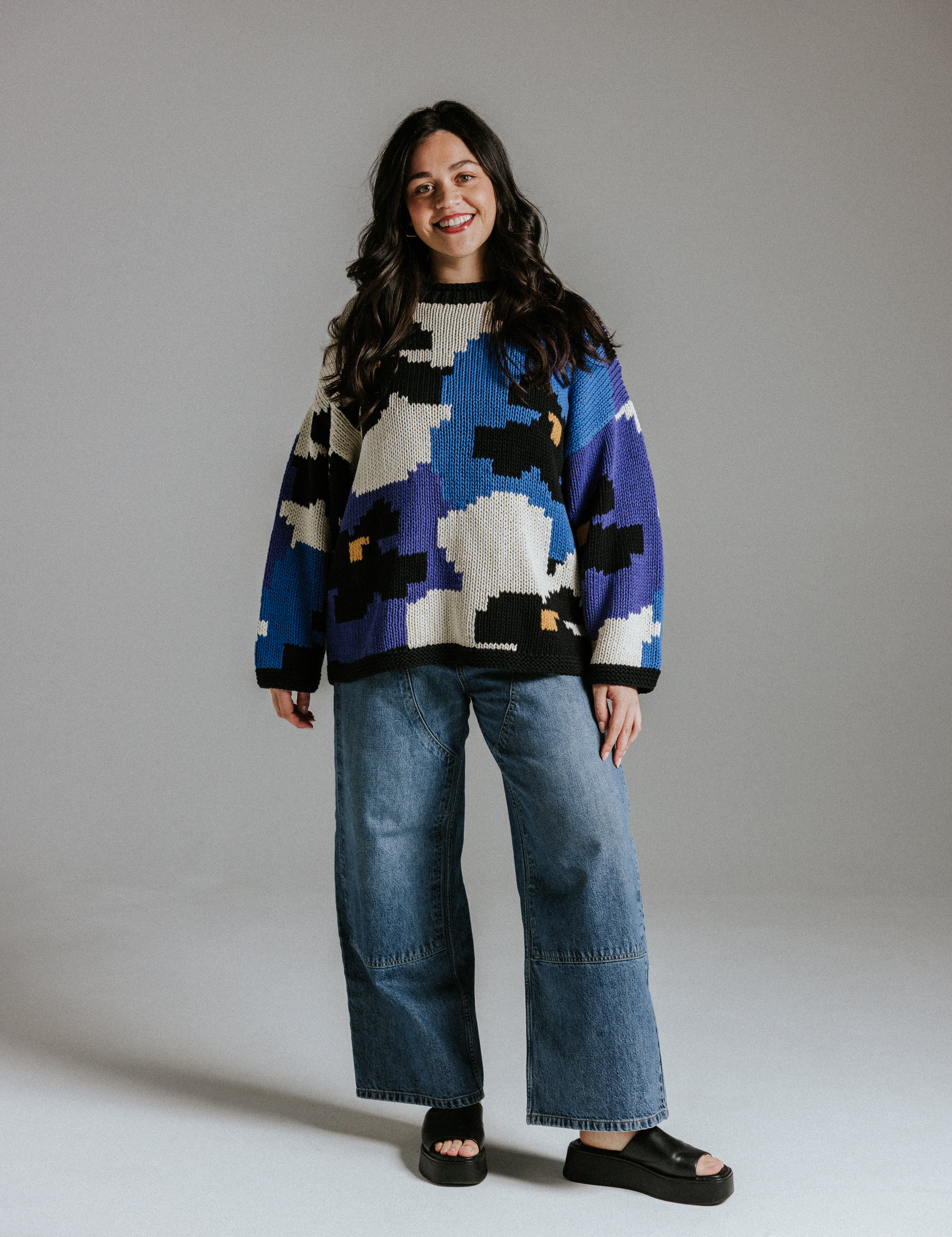 Model wearing hand knitted cotton jumper with floral intarsia pattern inspired by Alice in Wonderland by Slow Love Knitwear