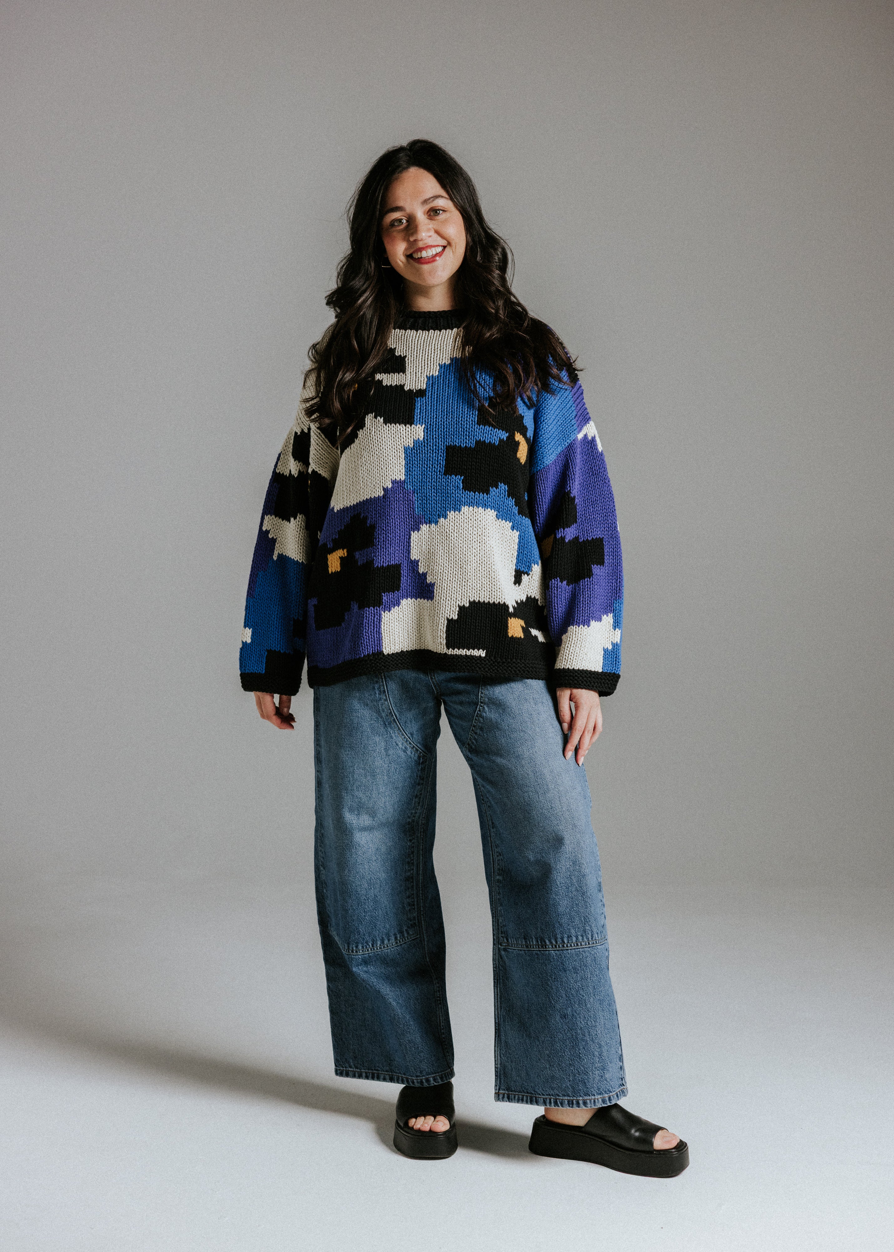 Model wearing hand knitted cotton jumper with floral intarsia pattern inspired by Alice in Wonderland by Slow Love Knitwear