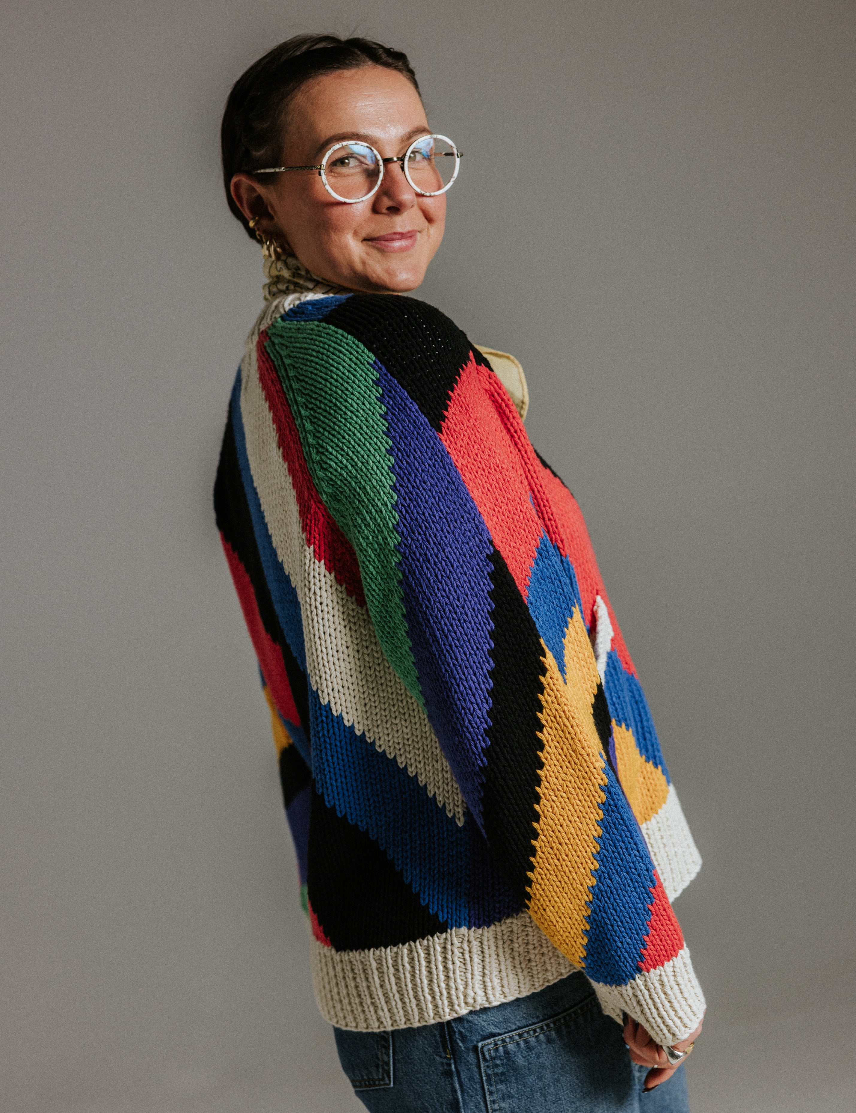 Side view of oversized handknit cotton cardigan by Slow Love Knitwear with seven colour intarsia stripe pattern