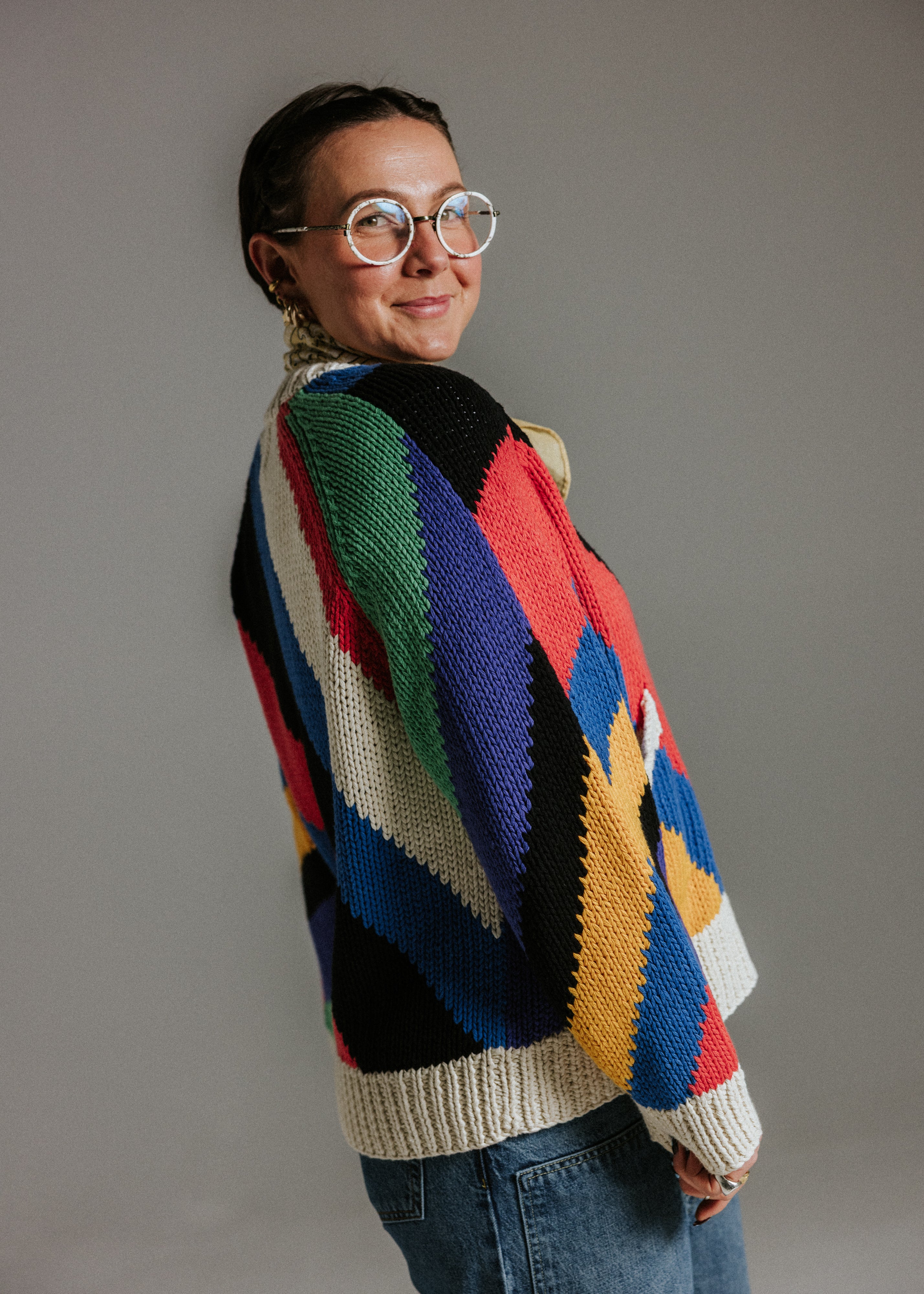 Side view of oversized handknit cotton cardigan by Slow Love Knitwear with seven colour intarsia stripe pattern
