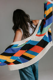 Model wearing oversized handknit cotton cardigan with seven colour intarsia stripe pattern by Slow Love Knitwear