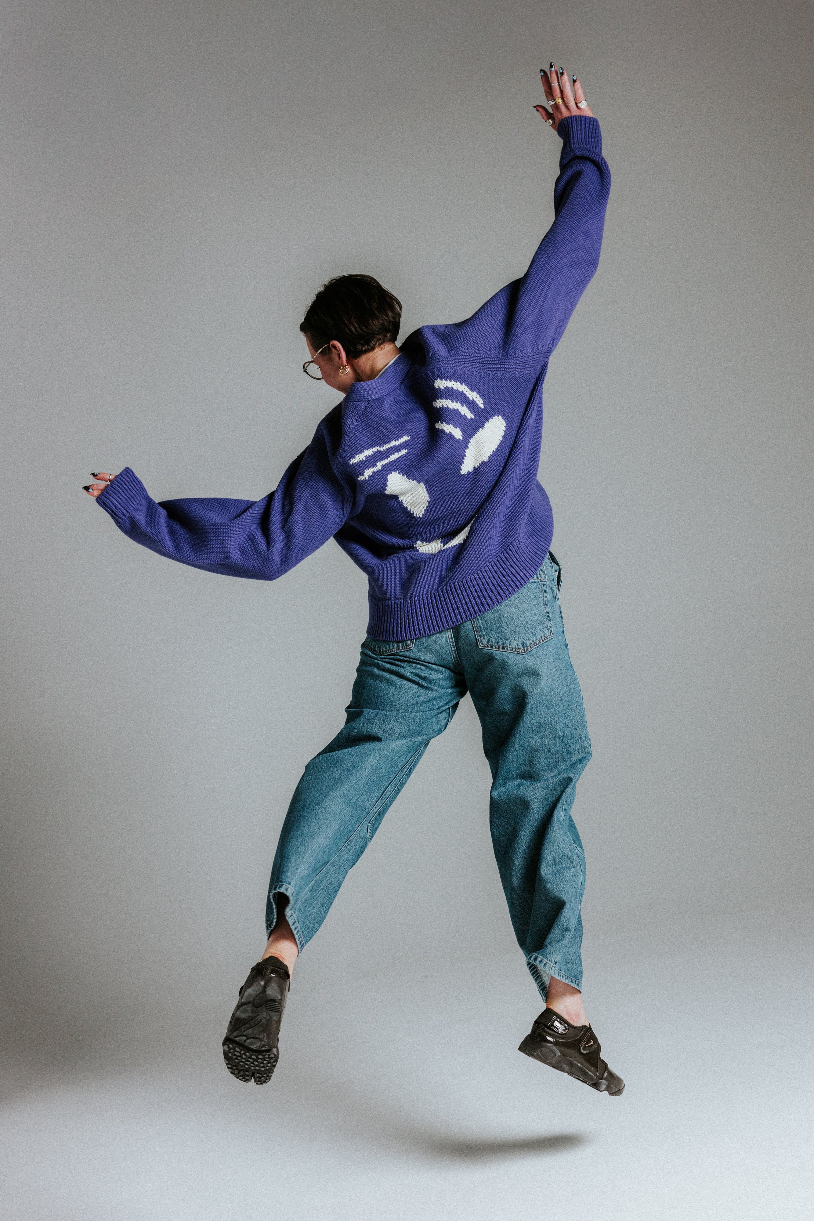 Model wearing oversized faded indigo and white smiley face cardigan by Slow Love Knitwear