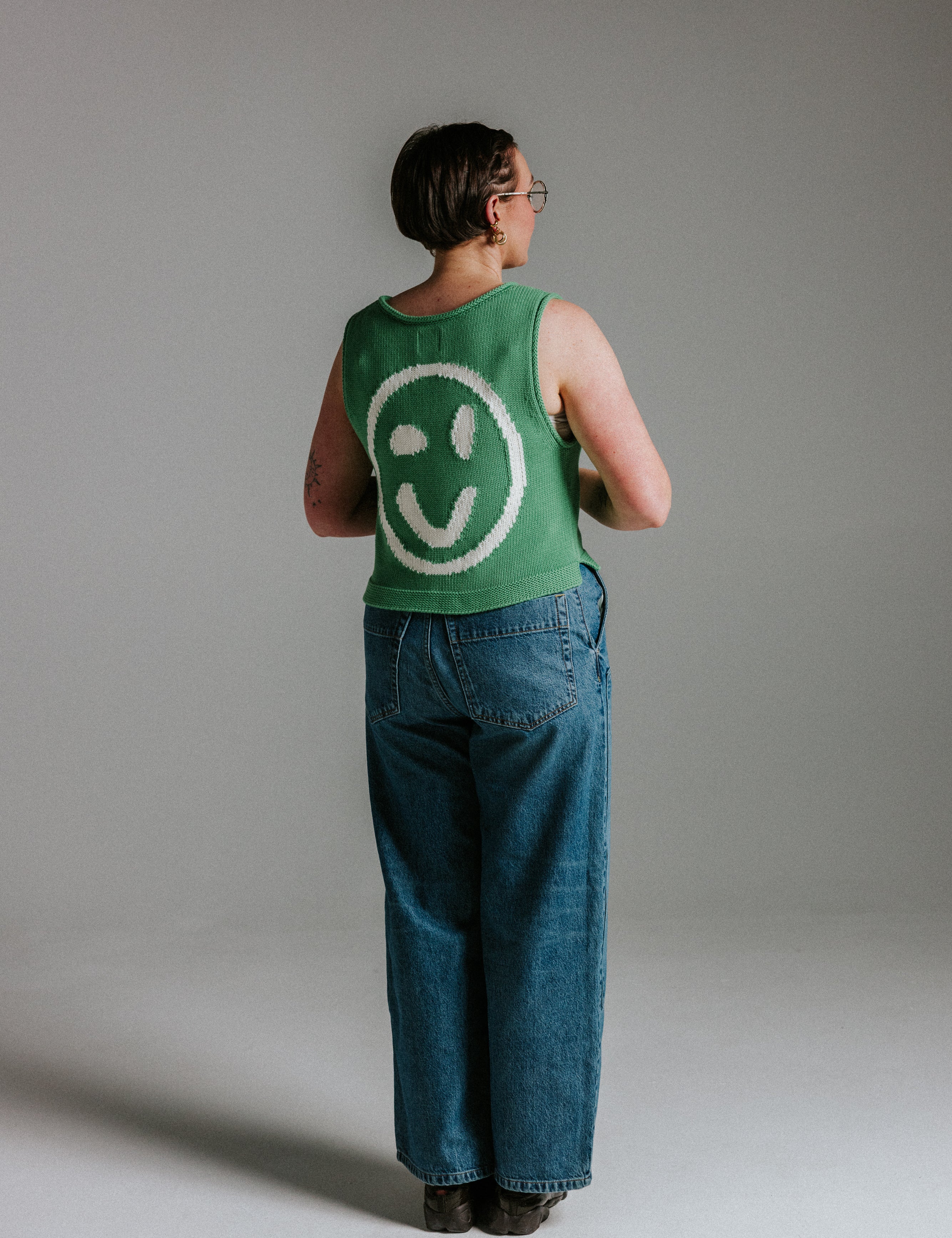 Back view of green and white cotton knit tank top by Slow Love Knitwear with smiley face design