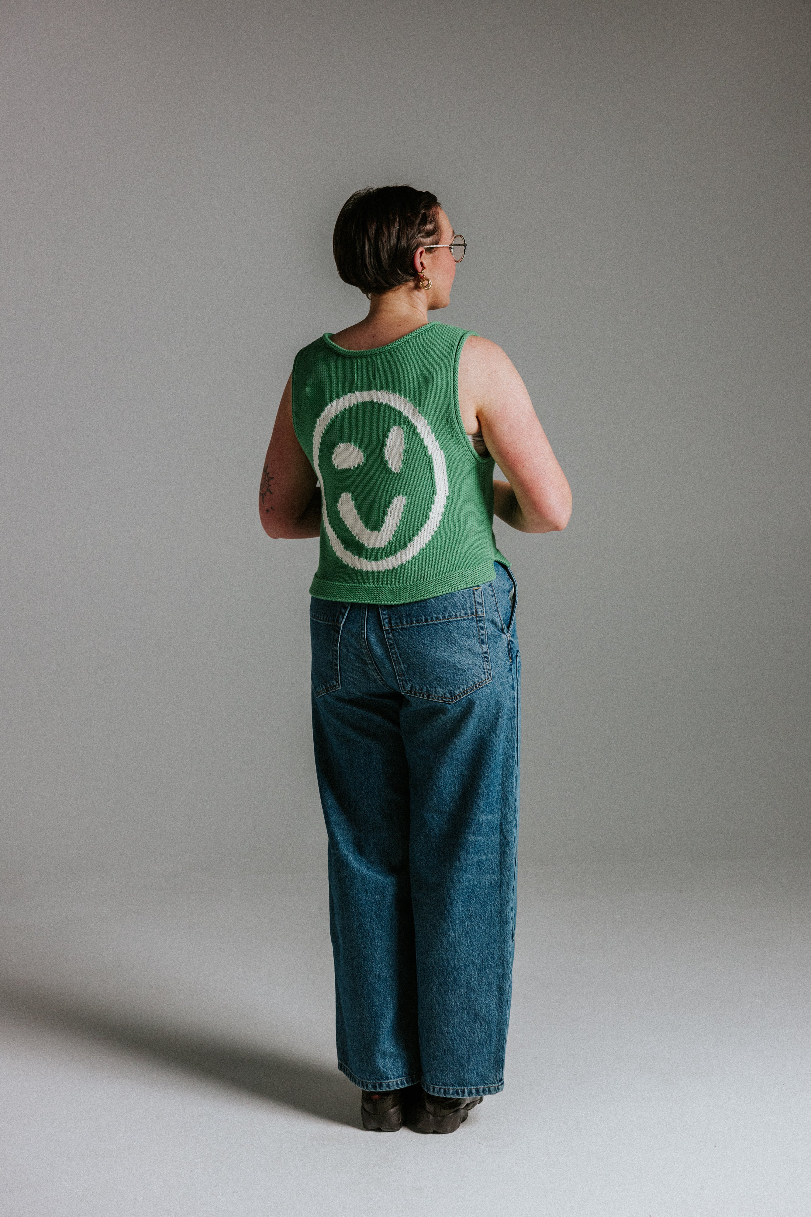 Back view of green and white cotton knit tank top by Slow Love Knitwear with smiley face design