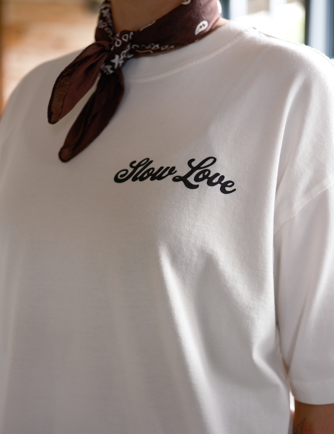 Close-up of Slow Love Script logo on off white heavyweight organic cotton t-shirt.