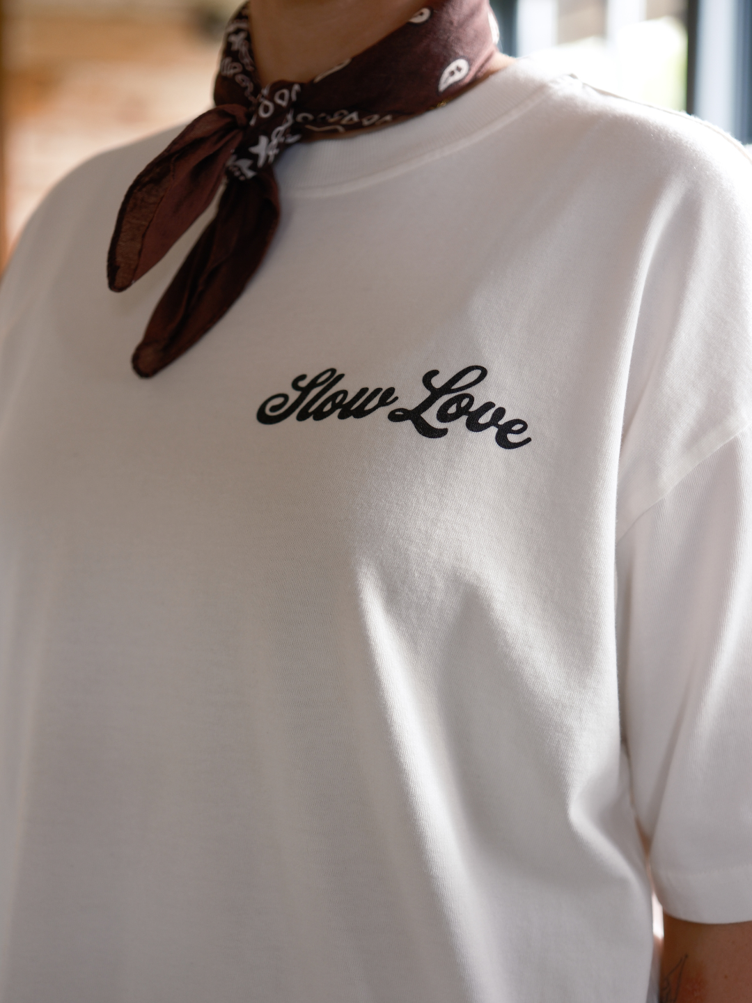 Close-up of Slow Love Script logo on off white heavyweight organic cotton t-shirt.
