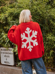 Close-up of the Ski Season Hand Knit Jumper by The Slow Love, showcasing its off-white alpine-inspired ski motif against a bold red cotton knit.