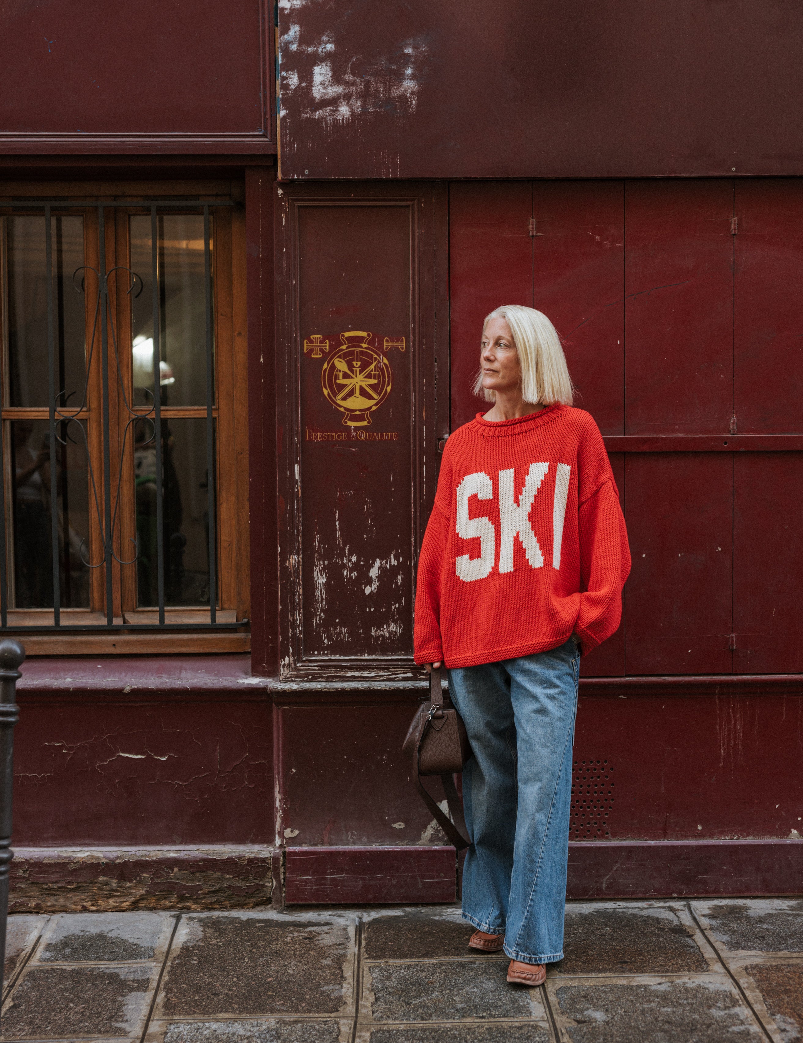 Red Ski Season Hand Knit Jumper by The Slow Love, featuring an off-white ski motif across the front, knitted from 100% cotton. 