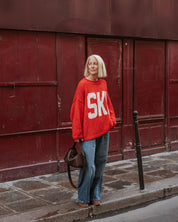 The Slow Love red Ski Season Hand Knit Jumper, a 100% cotton hand knit with a nostalgic alpine design and relaxed silhouette.