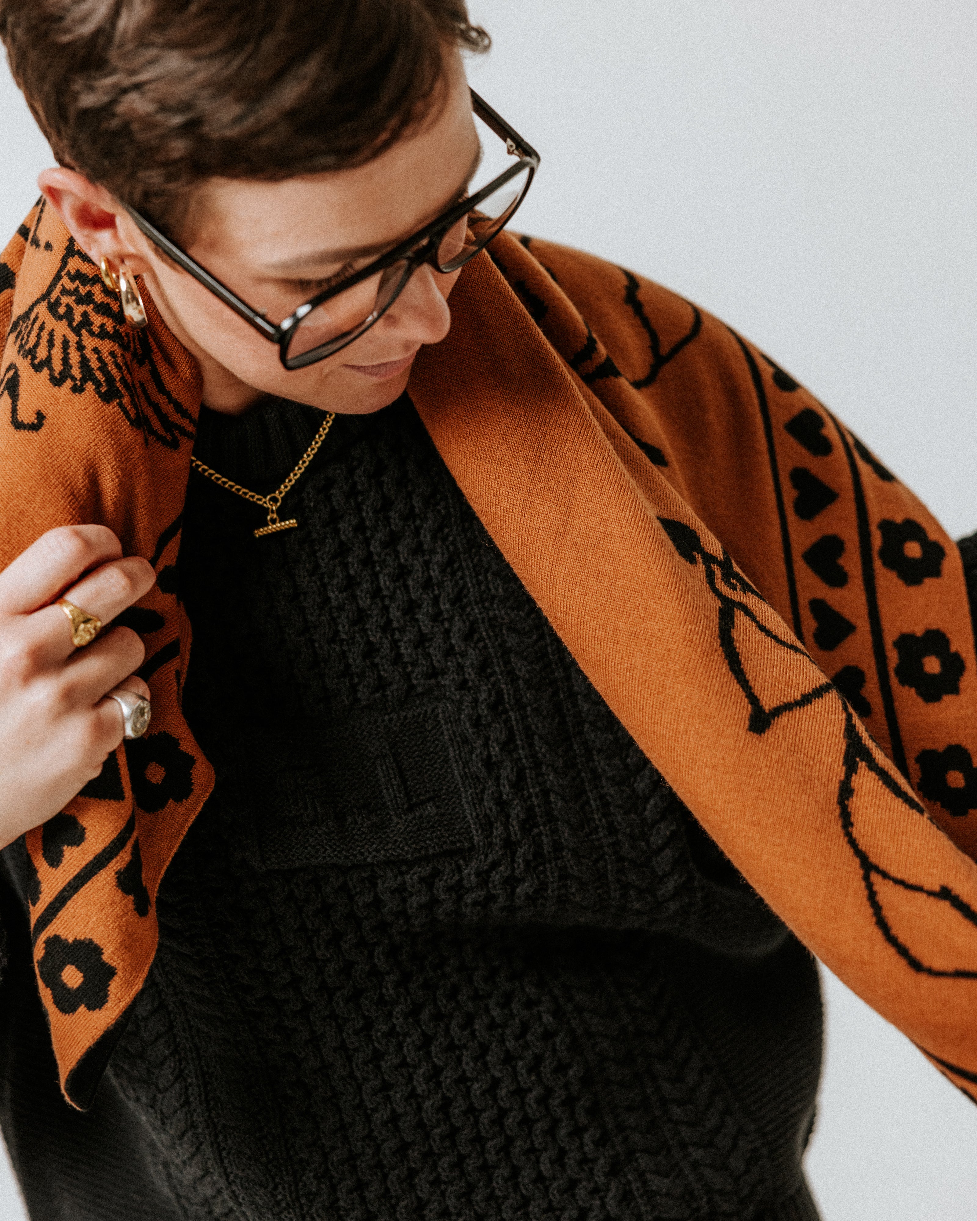 Close-up of The Slow Love Cherub Scarf in toffee and black, showcasing its intricate design and knitted merino wool texture.
