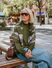 The Slow Love Wolf Bandana Scarf in olive green and lilac, featuring an illustrated wolf motif knitted from 100% fine gauge merino wool.