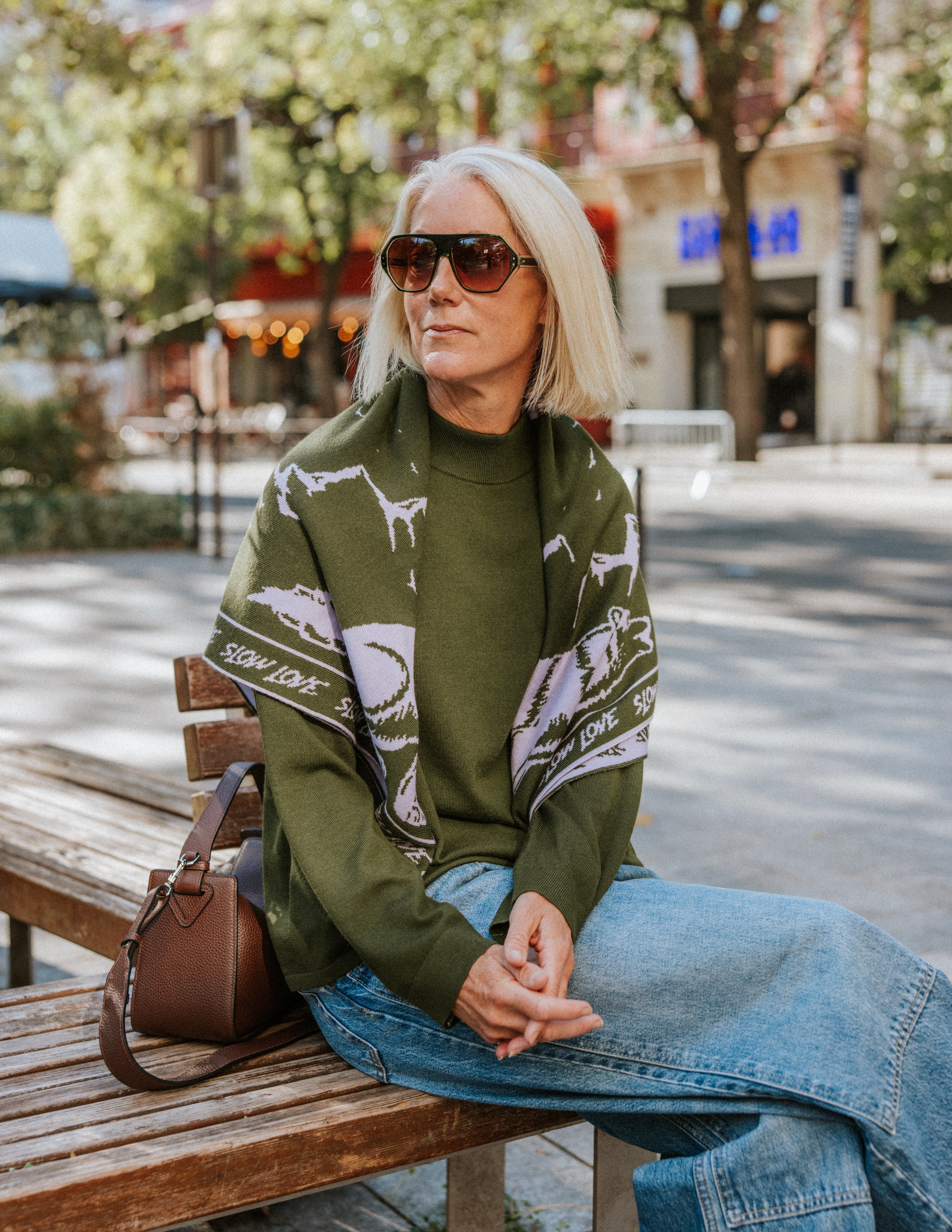The Slow Love Wolf Bandana Scarf in olive green and lilac, featuring an illustrated wolf motif knitted from 100% fine gauge merino wool.