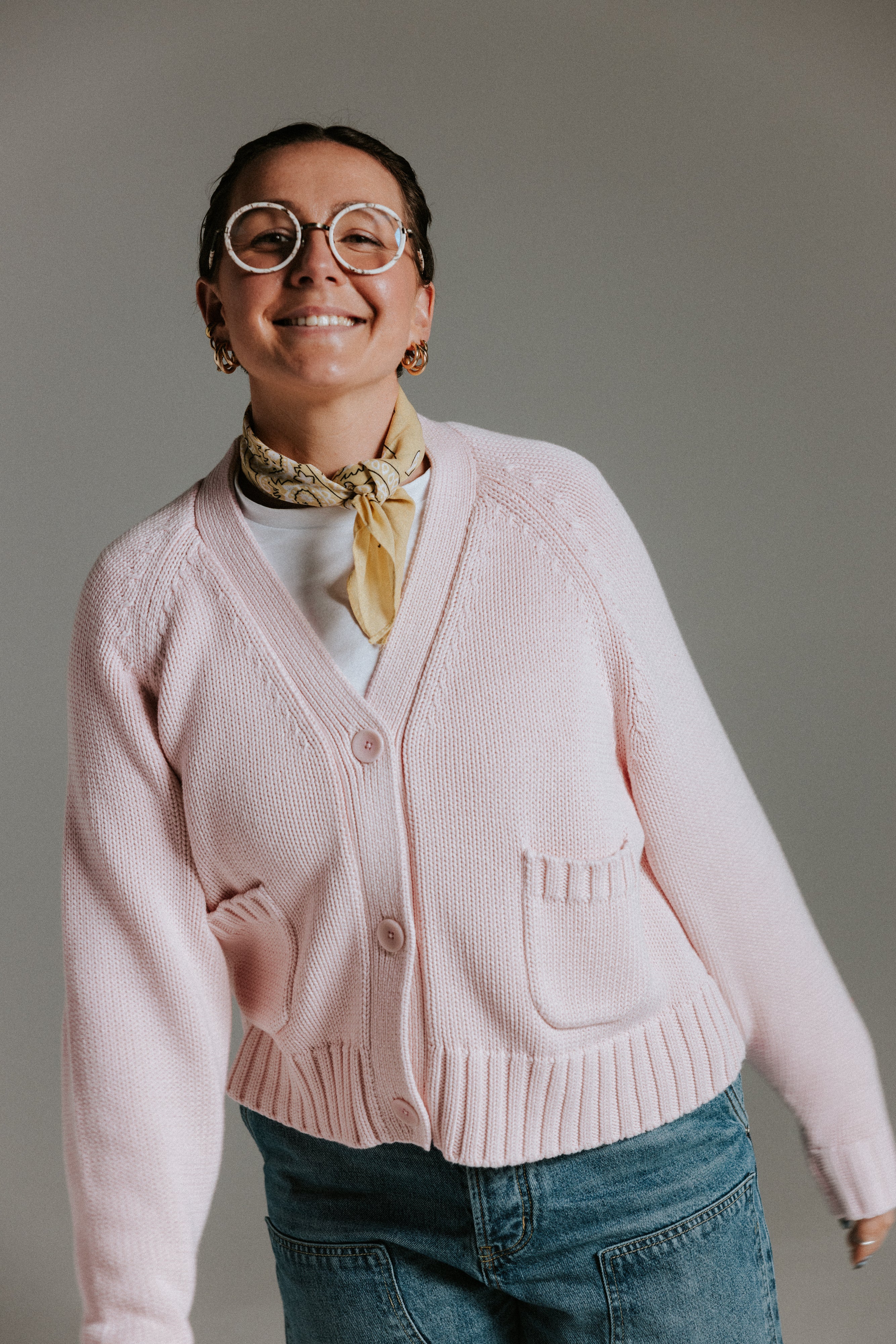 Model wearing The Staple Cardigan in mallow, a relaxed pink cotton knit cardigan with a slightly cropped fit