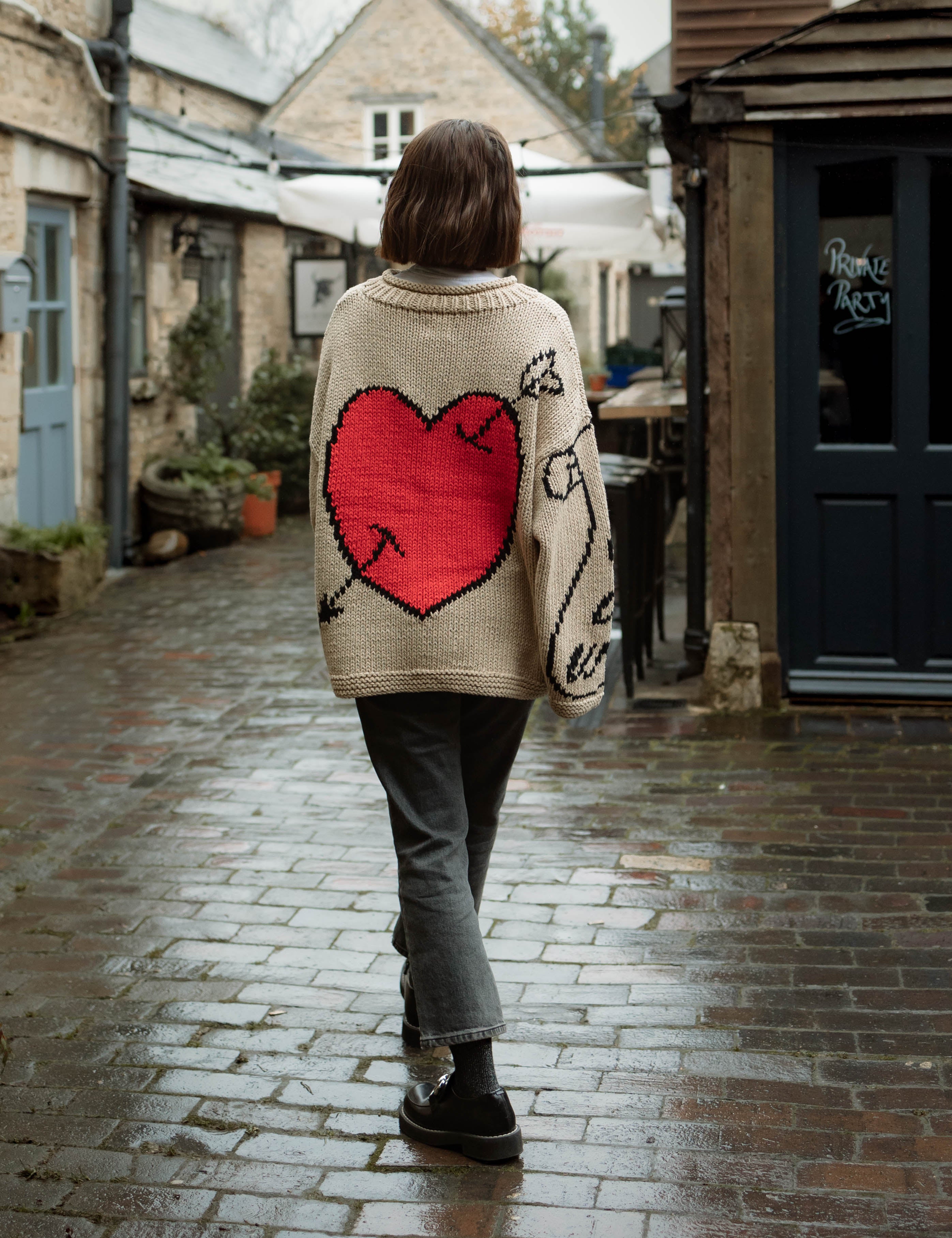 Lifestyle image of model wearing ecru Young Hearts hand knit jumper back view