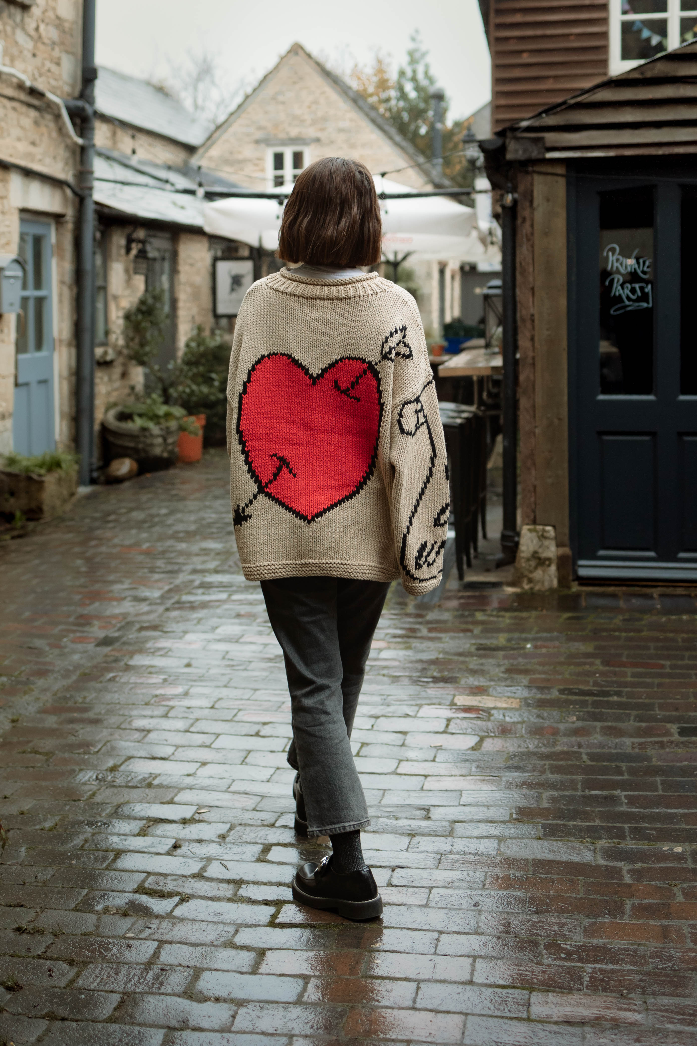 Lifestyle image of model wearing ecru Young Hearts hand knit jumper back view