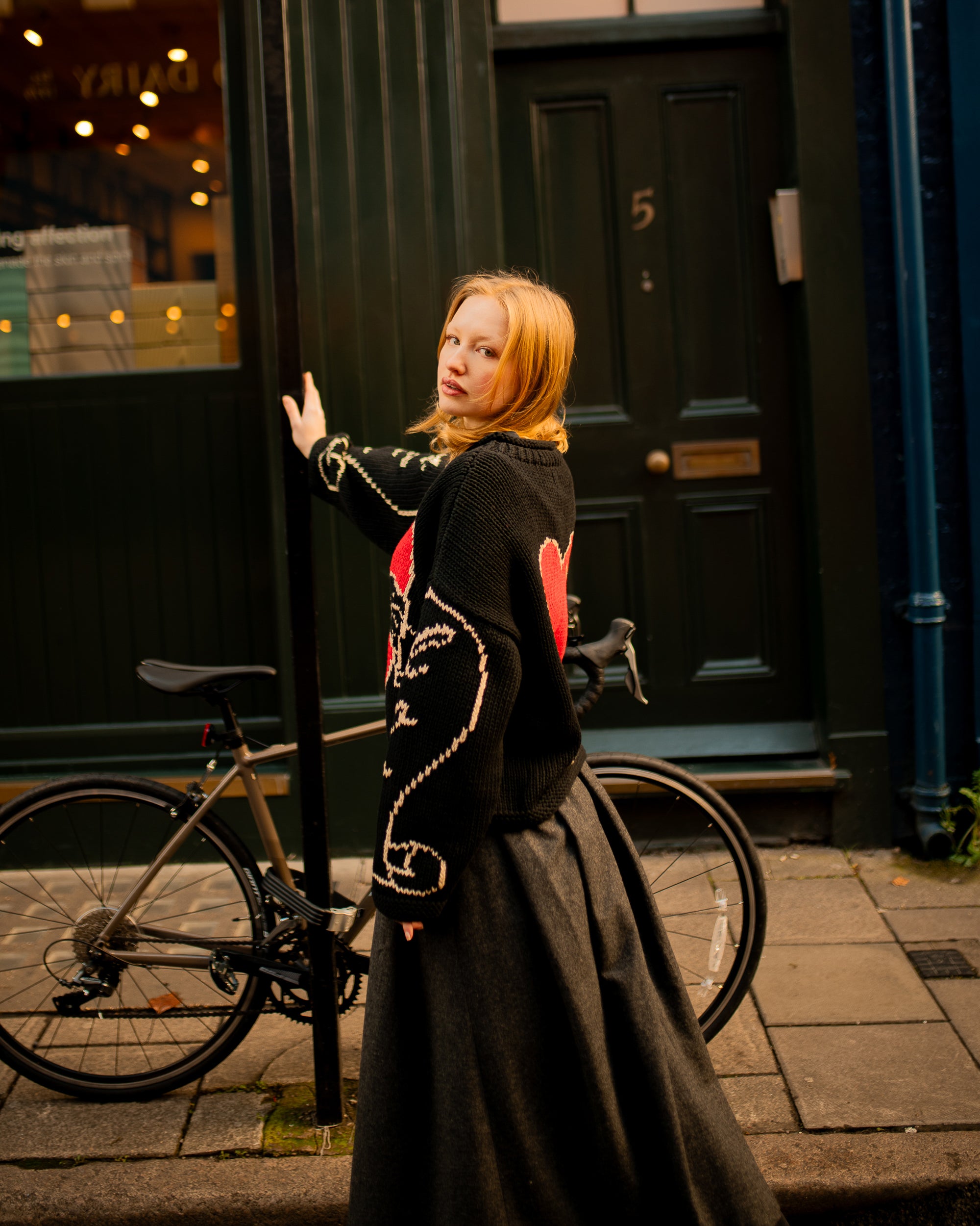 Side profile of model wearing black oversized hand knit jumper