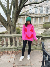 Pink and red oversized cotton jumper draped on model showing relaxed fit